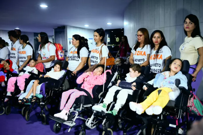 Familiares de crianças que tiveram sequelas pelo zika vírus fazem ato em favor da derrubada do veto ao projeto que concede ajuda financeira às famílias de crianças que tiveram sequelas pelo zika vírus (PL 6064/2023). A medida foi vetada integralmente pelo presidente da República em janeiro de 2025 e, no lugar, o Palácio do Planalto editou uma medida provisória que concede uma indenização de R$ 60 mil, o que exclui o benefício financeiro contínuo. Manifestantes usam camisa que diz: "Amizica Não ao veto do PL 6064/2023".