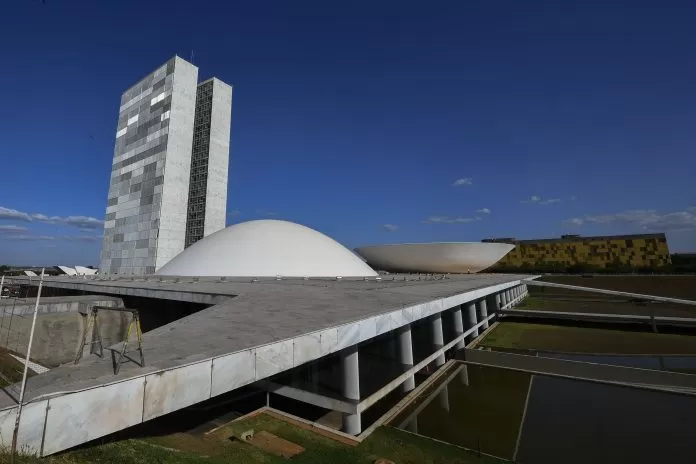 Fachada do Palácio do Congresso Nacional. O Palácio do Congresso Nacional é um dos pilares da arquitetura monumental de Niemeyer que dão forma à capital inaugurada em 1960. Construído em terreno elevado, é visto de longe como culminância da avenida Eixo Monumental, que abriga a Esplanada dos Ministérios e atravessa a cidade de norte a sul. Sede das duas Casas do Poder Legislativo e um dos mais famosos cartões postais do Brasil, o Palácio do Congresso Nacional é composto por duas cúpulas e duas torres de 28 andares, que abrigam a Câmara dos Deputados e o Senado Federal.